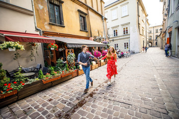 a young couple is stylishly dressed, a girl in a red dress, a man in a blue shirt and blue pants, walk the streets in Krakow Poland - obrazy, fototapety, plakaty