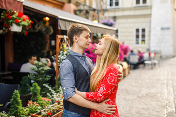 a young couple is stylishly dressed, a girl in a red dress, a man in a blue shirt and blue pants, walk the streets in Krakow Poland