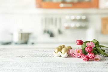 Easter eggs, tulips on kitchen white wooden table. Spring composition. Space for design.