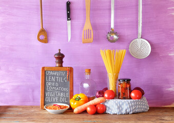 Italian food, ingredients for spaghetti dish with vegetables, red lentils and sun-dried tomatoes, recipe written on kitchen black board