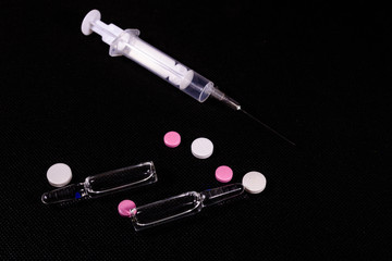 Syringe and pills on a black background. Healthcare and medicine concept