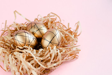 Easter golden decorated eggs in nest on white background . Minimal easter concept copy space for text. Top horizontal view, flatlay.