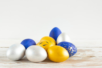 Christ is risen. Easter eggs painted in silver, gold and blue on a white wooden table. Holiday card.