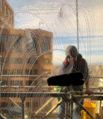 Window washer cleans a high rise office window in the morning with a splash.