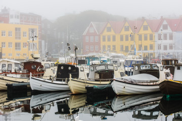 Fototapeta na wymiar Boats in harbour at a misty Torshavn city, Faroe Islands