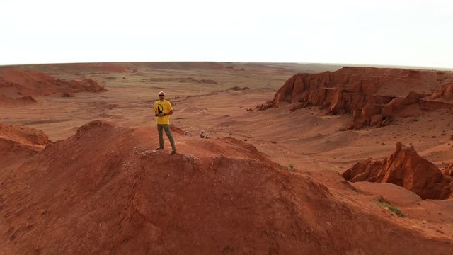 Aerial view of a man in a canyon in the Gobi Desert at sunset. Mongolia, Gobi, Bayanzag valley, Flaming Cliffs. Drone footage