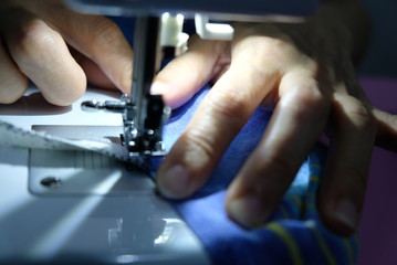 A tailor is sewing clothes with a sewing machine.