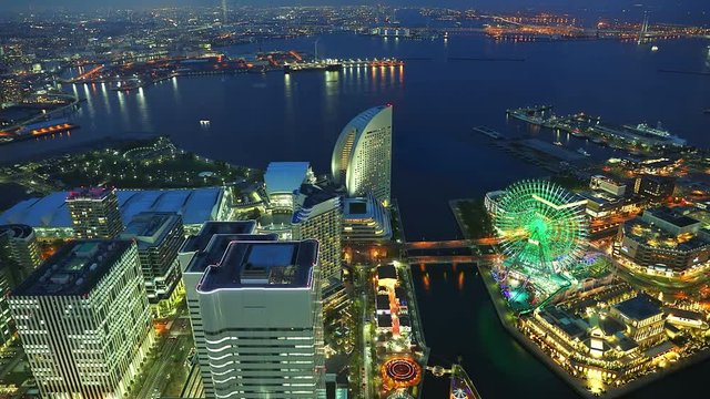 TIMELAPSE: Aerial view of Yokohama Cityscape and Yokohama Skyline from sunset to night by Landmark Tower. Skyscrapers from observatory sky garden. Illuminated ferris wheel and roads.