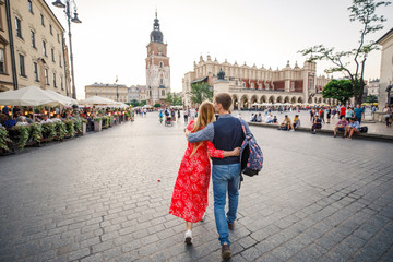a young couple is stylishly dressed, a girl in a red dress, a man in a blue shirt and blue pants, walk the streets in Krakow Poland - obrazy, fototapety, plakaty