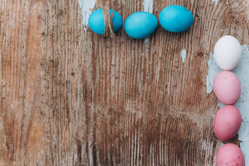 Pink and blue chicken easter eggs on old wooden plain background.
