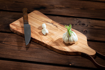 Sprouted Garlic on a cutting board with a knife.