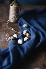 quail eggs on a dark wooden background decorated with blue cloth