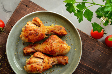 Fried chicken legs in a gray plate. Grilled chicken legs. Crispy crust. Top view. Wood background. Horizontal view.