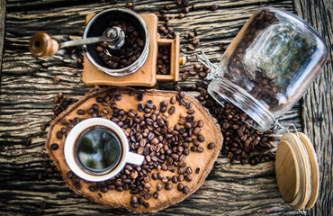 Black coffee in a white cup With freshly roasted coffee beans spilled on a wooden table