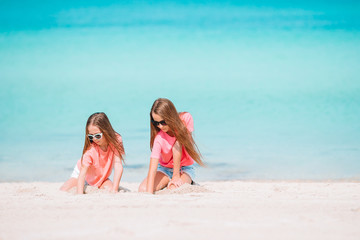 Little happy funny girls have a lot of fun at tropical beach playing together.