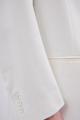 Person in a classic white blazer closeup. Pocket and buttons. Vertical photo.