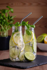 Refreshing drink or water with citrus fruits lemon and lime and basil herb in mason jar with reusable metal straws. Healthy lemonade drink in glass jar, zero waste concept, sustainable lifestyle