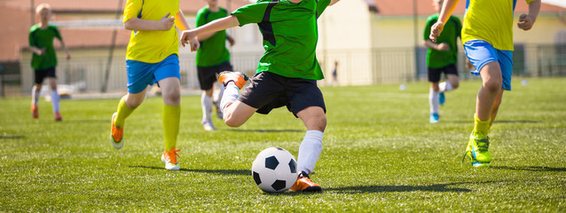 Kids in soccer teams kicking ball on sports venue. Children compete in sports school tournament....