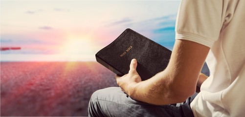 Man reading old Bible book on background