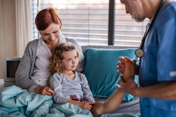 Obraz premium Doctor examining a small hospitalized girl with mother in hospital.