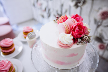 Beautifully decorated catering banquet table with white cake with red flowers on the top.