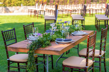 Beautifully decorated wooden table in a summer open-air cafe. Green branch and fresh flowers table decoration
