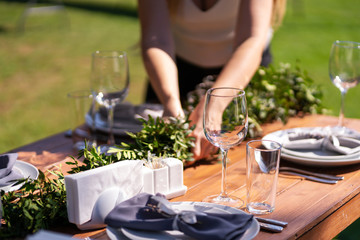 Preparing for an open-air party. Girls decorators decoration with fresh flowers on served tables. Decoration Details