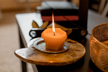 A scented wax candle on a stand is on the table. Relaxation, meditation.