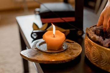 A scented wax candle on a stand is on the table. Relaxation, meditation.