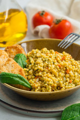 Homemade Ptitim with chicken schnitzel. Ptitim - or Israeli couscous - toasted paste. Made with fried onion, carrot, tomato and spinach.