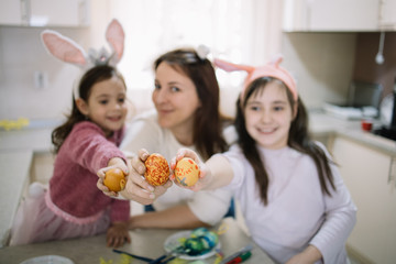 Obraz na płótnie Canvas Blurred mother and daughters holding on focus eggs