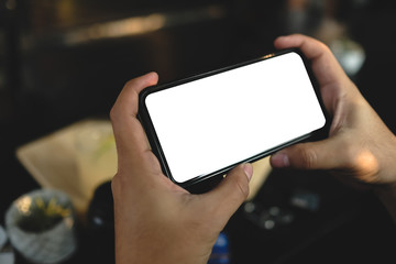 Close up of man using cell phone,sending massages on the coffee shop with black screen,texting,video calls.