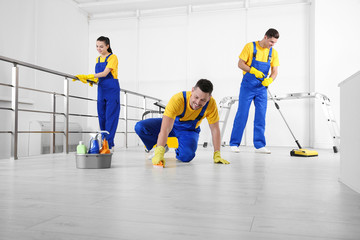 Team of professional janitors cleaning room after renovation