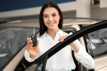 Fototapeta na wymiar Saleswoman with key near car in dealership, focus on hand