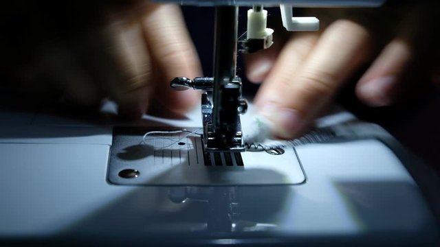 A tailor is sewing clothes with a sewing machine.
