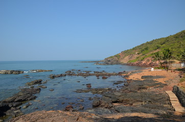 Fototapeta na wymiar Nature in North Goa. India. Red earth, volcanic rocks and boulders. Beautiful blue sea. Vacation concept in India.
