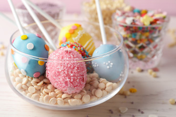 Egg shaped cake pops for Easter celebration on white wooden table, closeup