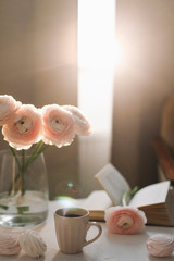 Spring still life. Coffee cup, flowers, book and marshmallows. Cozy home decor. Concept of holiday, birthday. Feminine flat lay