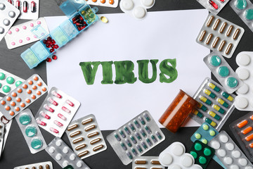 Paper with word VIRUS and many different pills on black background, flat lay