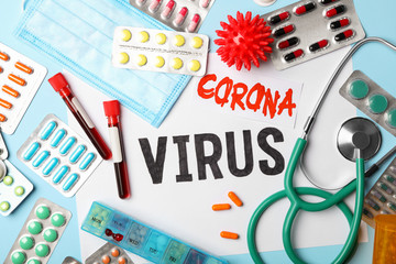 Flat lay composition with phrase CORONA VIRUS and medicines on light blue background