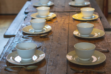 plates bowls and cutlery on a wooden table ready for food to be served
