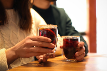 Lovely couple with tasty mulled wine at table in cafe, closeup