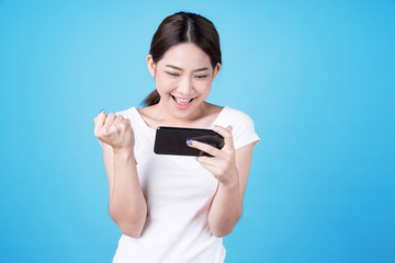 Lovely Asian woman looks down at the mobile phone and shows a happy face, Isolated on a blue background.