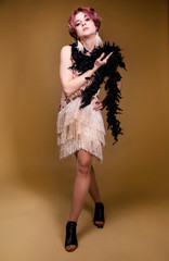 Beautiful retro woman from the roaring 20s is posing on the beige background
