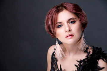 Fototapeta premium Beautiful retro woman from the roaring 20s is posing on black background
