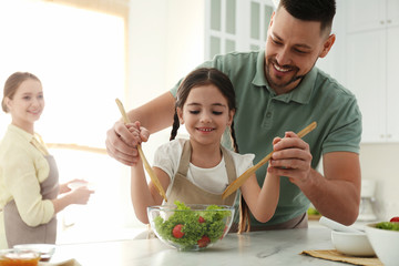 Happy family cooking salad together in kitchen