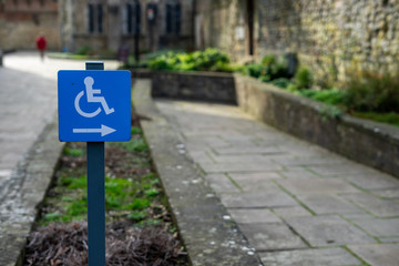 A disabled sign pointing to a wheelchair ramp on a path