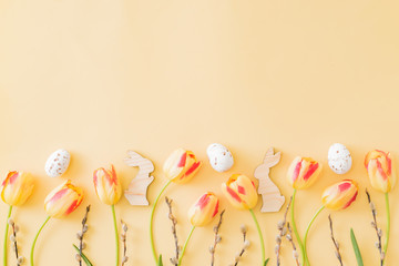 Flat lay easter composition with yellow tulips and eggs on a yellow background