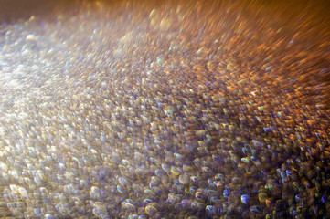 Orange and lilac glitter cardboard in defocus. Abstract light background.