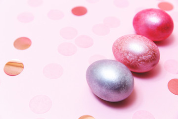 Three Easter eggs on the pink table .